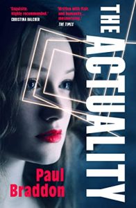 Cover of The Actuality displays anear perfect lifelike female android wearing bright red lipstick, blue eyes and dark hair. The title is in bold white lettering, virtically on the right.